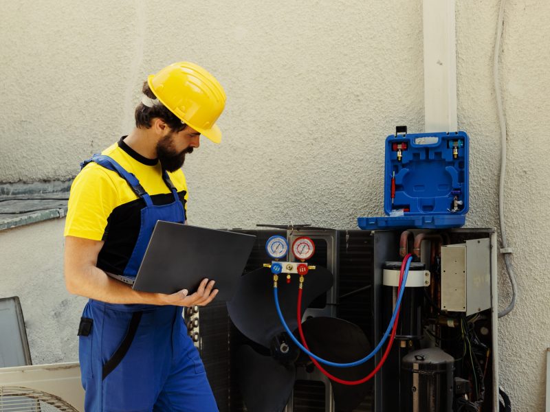 trained-engineer-tasked-with-servicing-outdoor-air-conditioner-internal-components-checking-freon-level-calibrating-thermostats-skilled-technician-looking-maintenance-plan-laptop-scaled.jpg